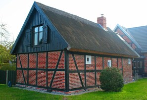 A traditional half-timbered house with a steeply pitched roof, a visible chimney, and a small window. - Holiday Home Monke's Kate Near Seabeach (Monkebude)