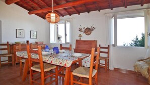Un comedor con una mesa y sillas de madera, una lámpara colgante y un ventanal con vistas.