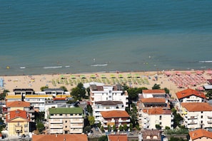 A coastal town with a beach, buildings, and a clear view of the sea.