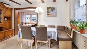 Un comedor con un aparador de madera, una mesa con mantel blanco y un banco para sentarse.