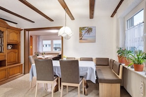 A dining area with a wooden cabinet, a table with a white tablecloth, and a bench seating area. - Apartment 'Pension Zum Europapark' with Mountain View, Shared Terrace and Wi-Fi (Teningen)