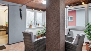 Una habitación con muebles de mimbre, techo de madera y una ventana con plantas.