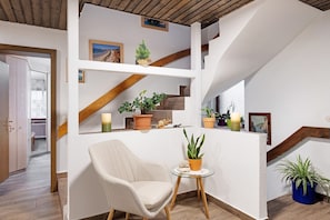 A modern interior with a staircase, a chair, and potted plants.