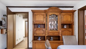 Una habitación con un armario de madera, una silla y una cama.