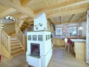A wooden interior with a kitchen, a fireplace, and a staircase.