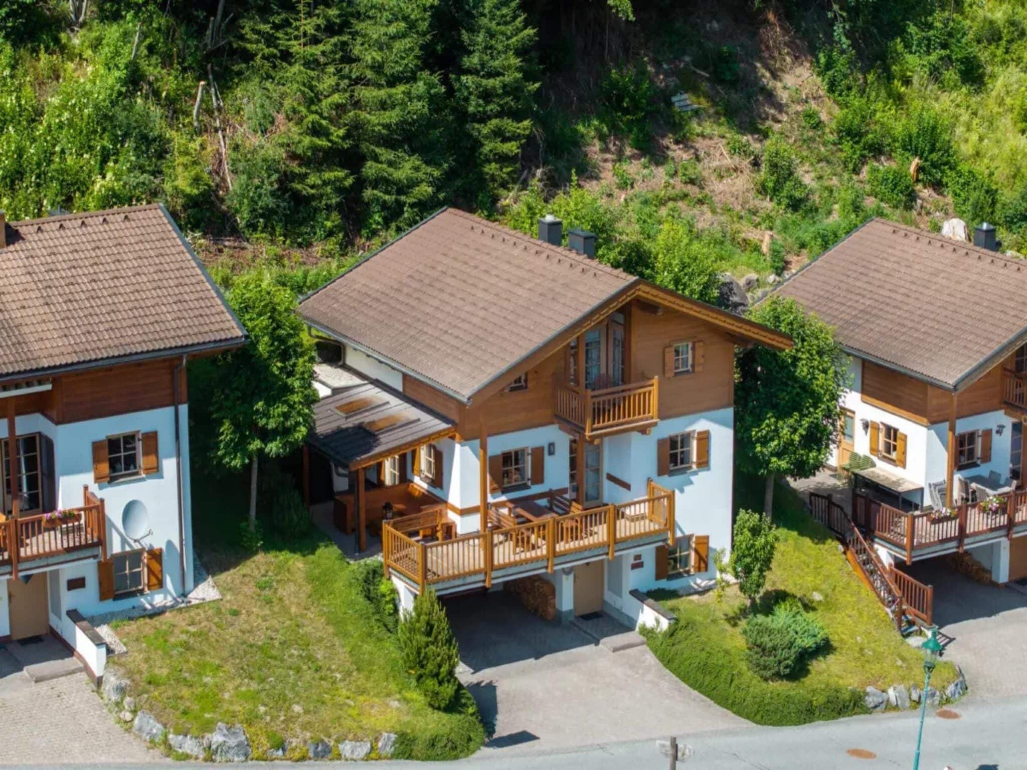 A cluster of wooden houses with balconies, surrounded by greenery.