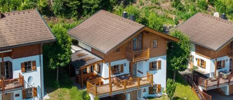 A cluster of wooden houses with balconies, surrounded by greenery.
