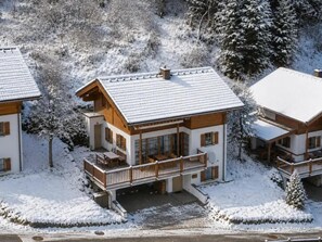 A chalet-style building with a balcony, surrounded by snow-covered trees.