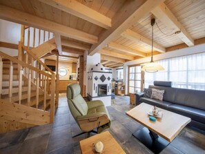 Un intérieur en bois avec un escalier, un coin salon et une cheminée.