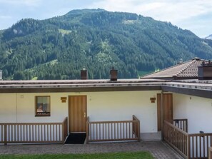 A building with a flat roof, wooden railings, and a view of a forested mountain.