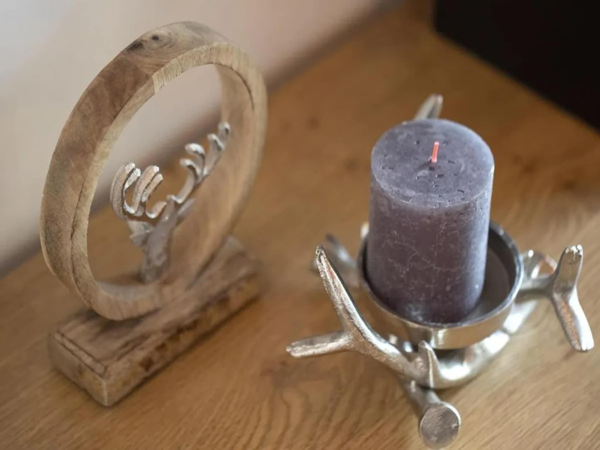 A wooden ring with a metal holder and a candle on a wooden surface.