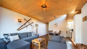 Una sala de estar moderna con techo de madera, un juego de sofá, una mesa de centro y un comedor con sillas.