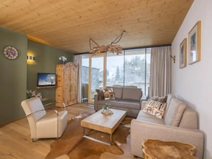 Una sala de estar acogedora con techo de madera, un sofá, una mesa de centro y un televisor.