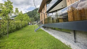A modern building with a wooden facade, a glass window, and a grassy area with trees.