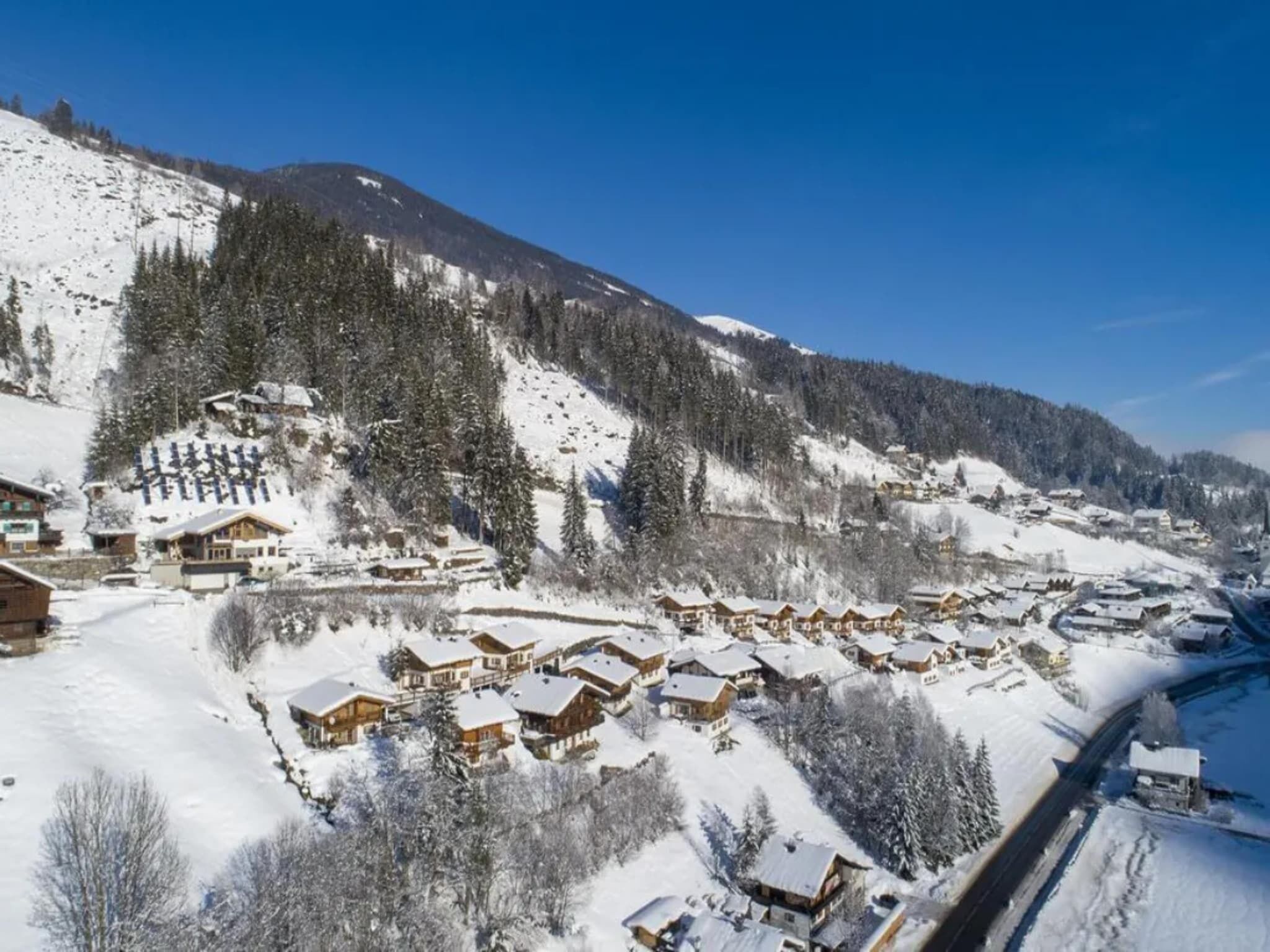 Un villaggio montano innevato con chalet in legno e una stazione sciistica.