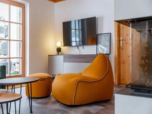 A modern living room with a sofa, a small table, and a television mounted on the wall.