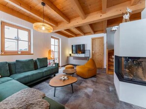 A modern living room with a green sofa, a round coffee table, and a fireplace.