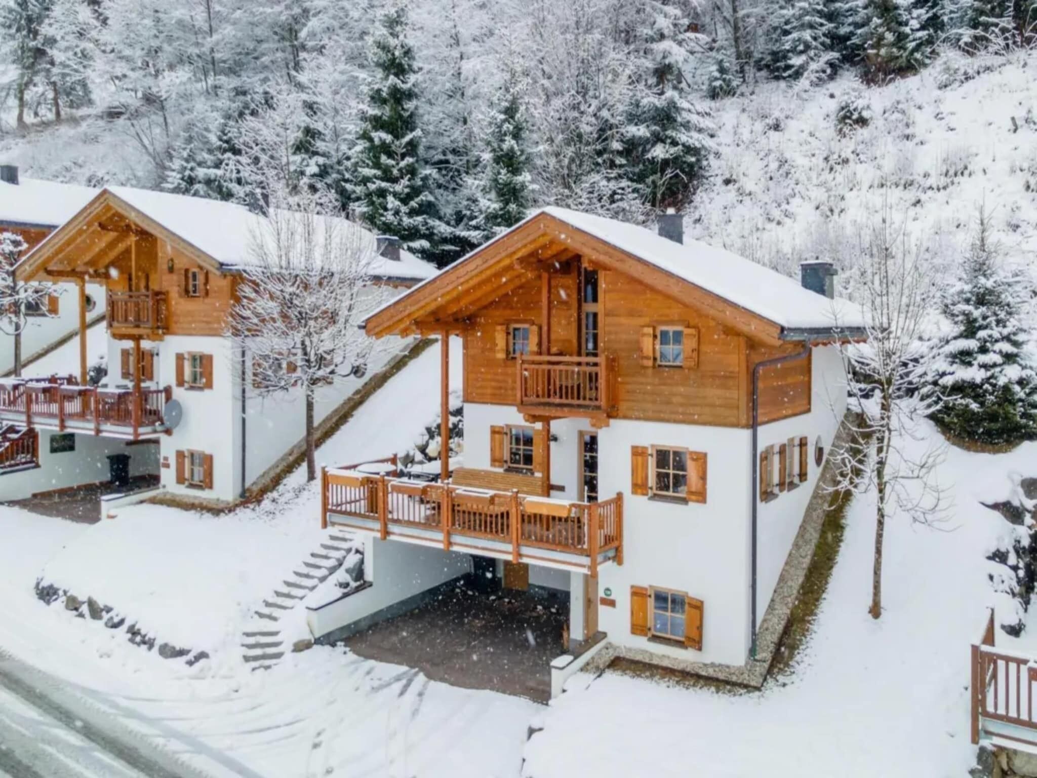 A wooden chalet-style building with a balcony, surrounded by snow-covered trees.