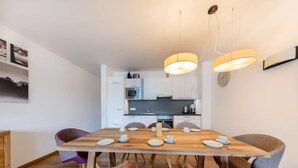 Un comedor moderno con una mesa de madera dispuesta para cuatro personas, rodeada de sillas tapizadas.