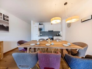 A modern dining area with a wooden table set for four, surrounded by upholstered chairs.