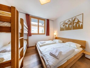 A room with bunk beds, a window with curtains, and a wall with mountain artwork.