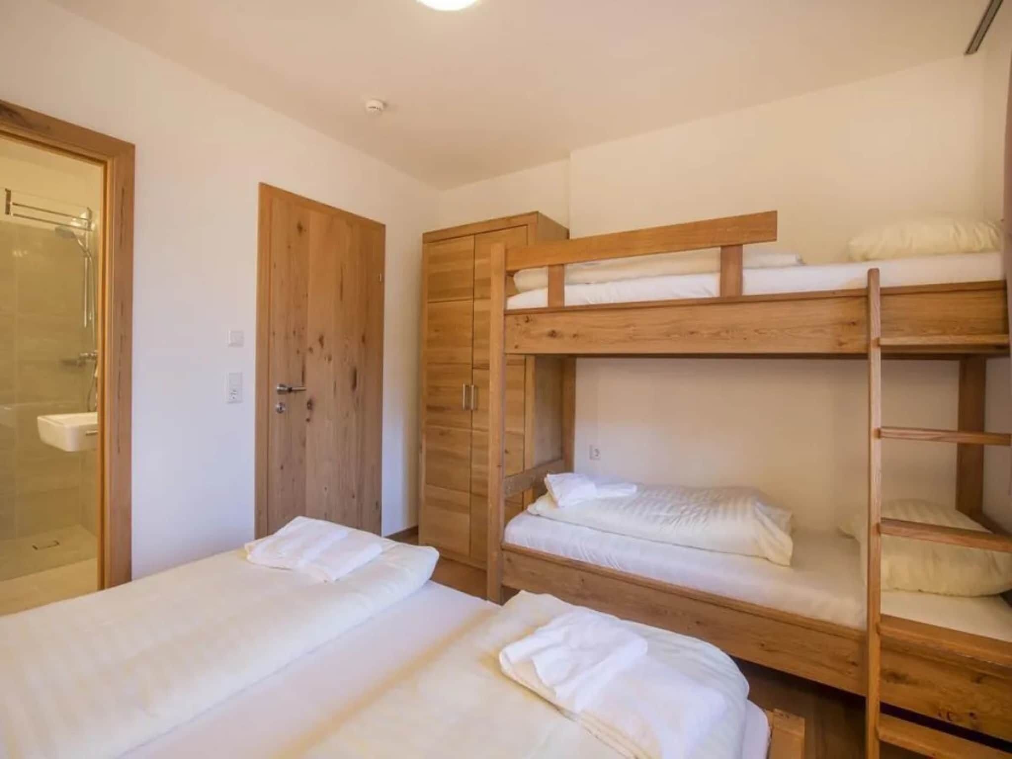 Una habitación con literas, un armario de madera y zona de ducha.