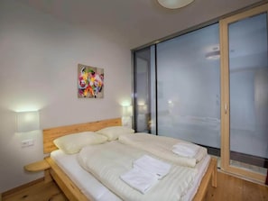Een slaapkamer met een bed, een schilderij en een schuifdeur met glas.