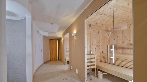 Un couloir avec un banc en bois, une cloison en verre et une porte donnant sur une autre pièce.