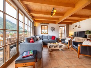 A spacious living area with a large window, a sofa, a coffee table, and a television.