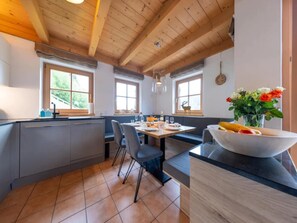 A modern kitchen with a central island, grey cabinetry, and large windows. - Stylish Ten-Person Alpine Chalet (Wald-Königsleiten)