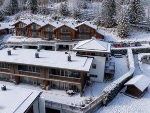 A modern multi-story hotel with a ski slope in the background.