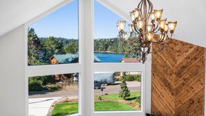 Ein Zimmer mit großen Fenstern und Blick auf einen Wald, einen See und eine Straße.