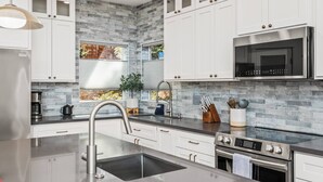 Eine moderne Küche mit weißen Schränken, einer Edelstahl-Spüle und einem eingebauten Backofen.