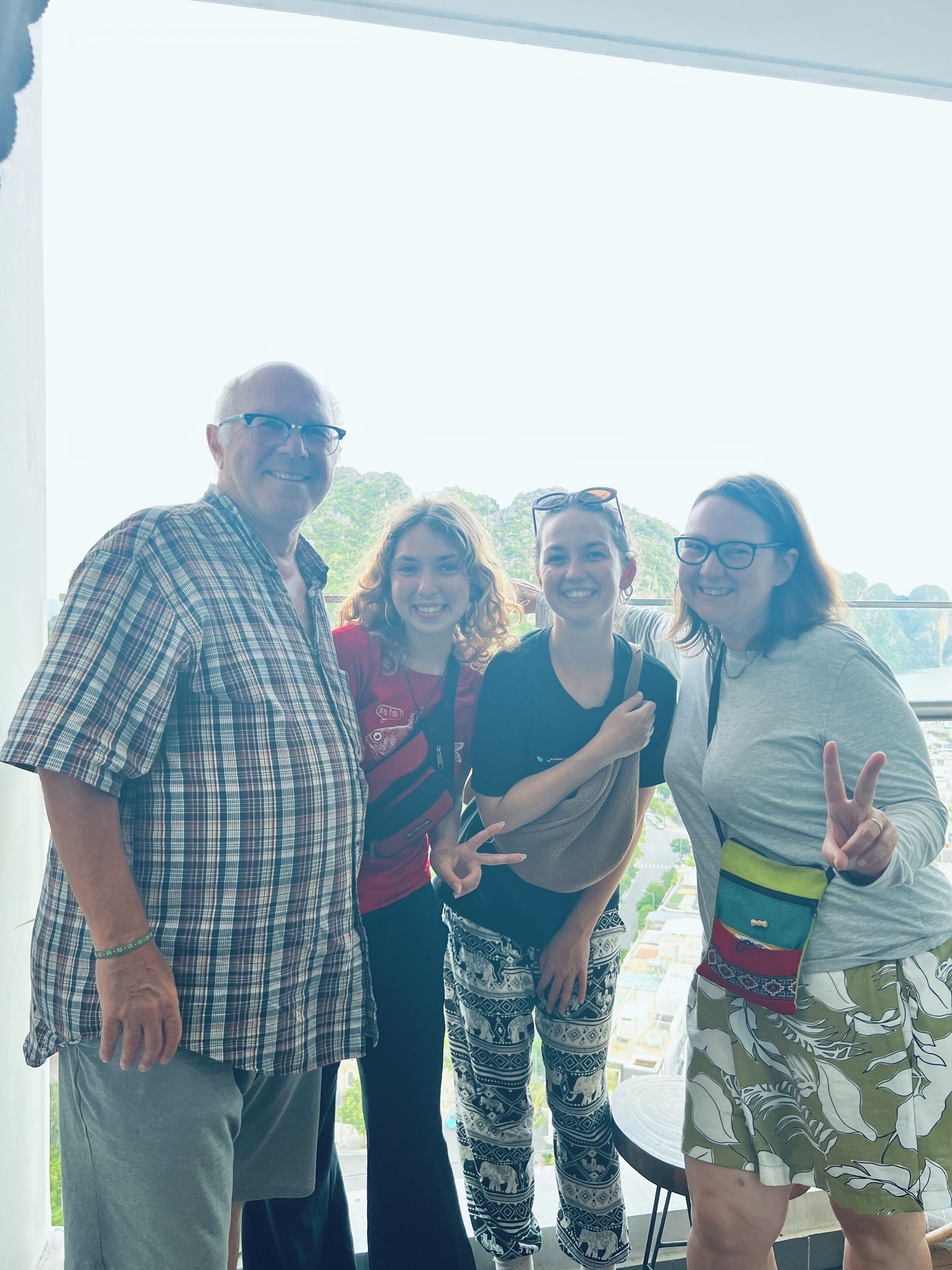 Een groep mensen staat op een balkon met uitzicht op groen en gebouwen.