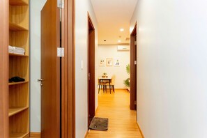 A hallway with wooden doors, a dining area with a table and chairs, and a mat on the floor. - Cozy Apartment Ha Long Bay (Ha Long)