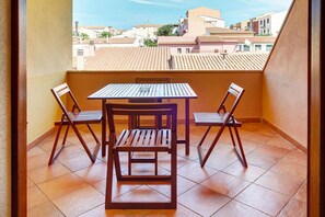 Un balcon avec une table et des chaises en bois, un sol carrelé et une vue sur les bâtiments.