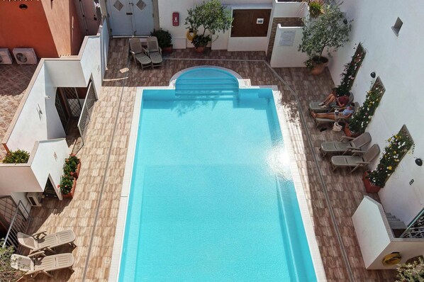 A rooftop pool with a clear blue water surface, surrounded by lounge chairs and potted plants. - Apartment in Santa Teresa Gallura (Santa Teresa di Gallura)