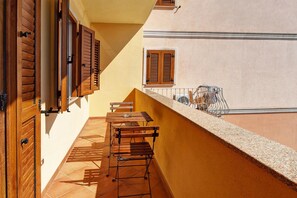 A balcony with wooden shutters, a table, and chairs.