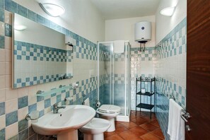 A bathroom with a checkered tile backsplash, a glass shower enclosure, a toilet, a sink, and a mirror.