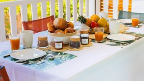 A breakfast table set with croissants, fruits, a pitcher of milk, and two glasses of orange juice.