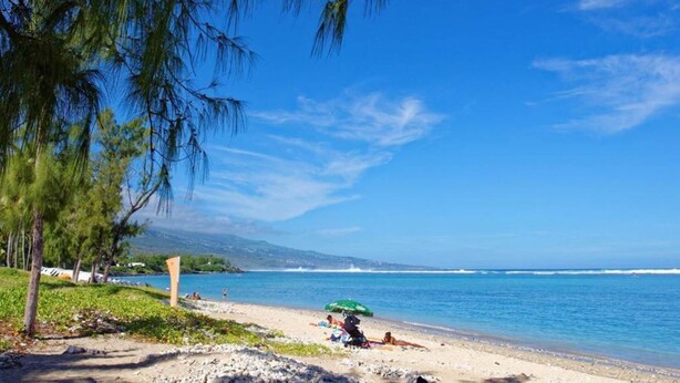 A beach with clear skies, calm water, and a few people sunbathing.