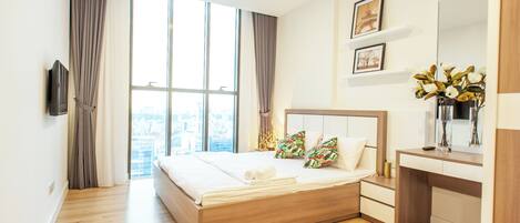 A modern hotel room with a large bed, a desk, and a city view.