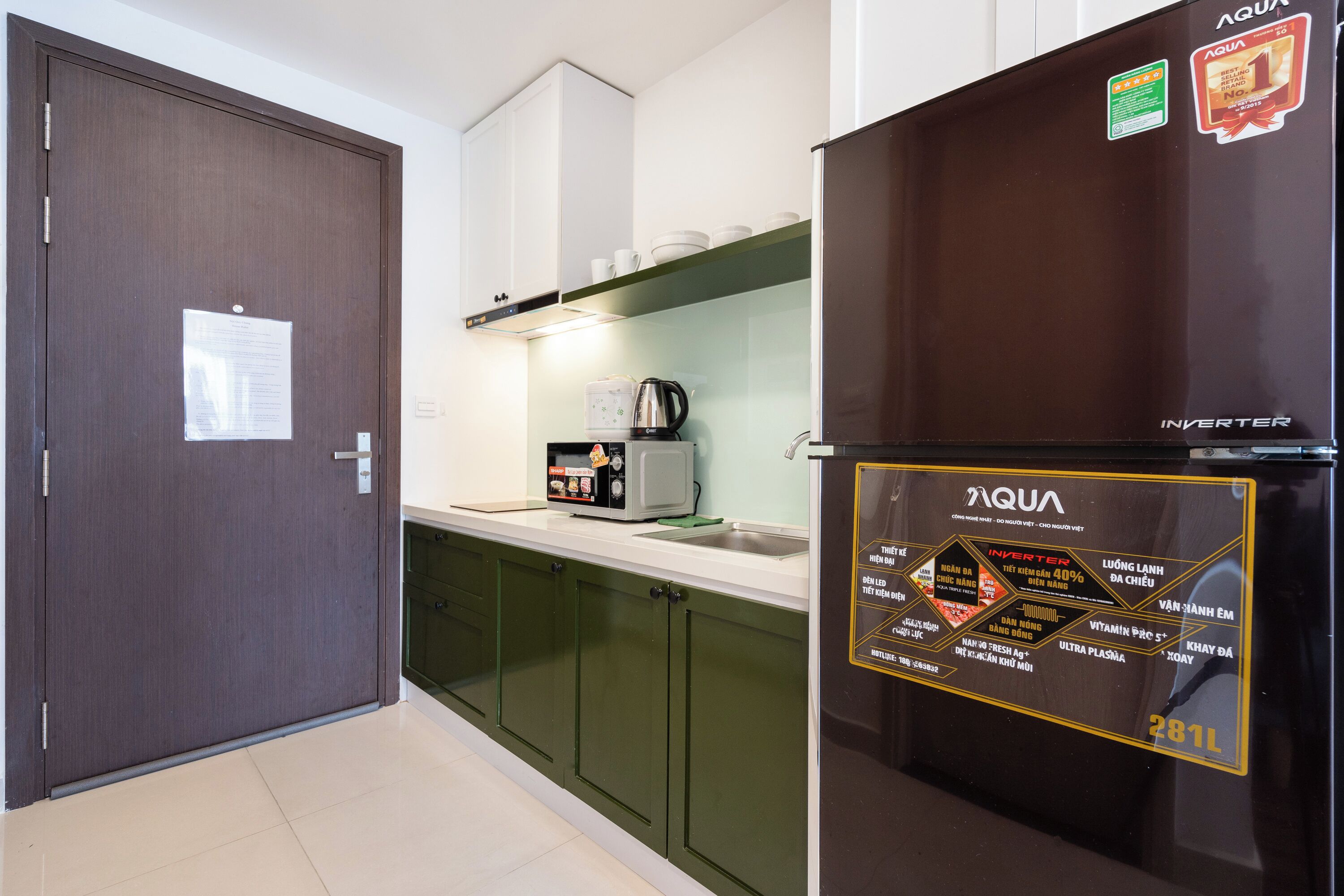 Una cocina con refrigerador, armarios y microondas.
