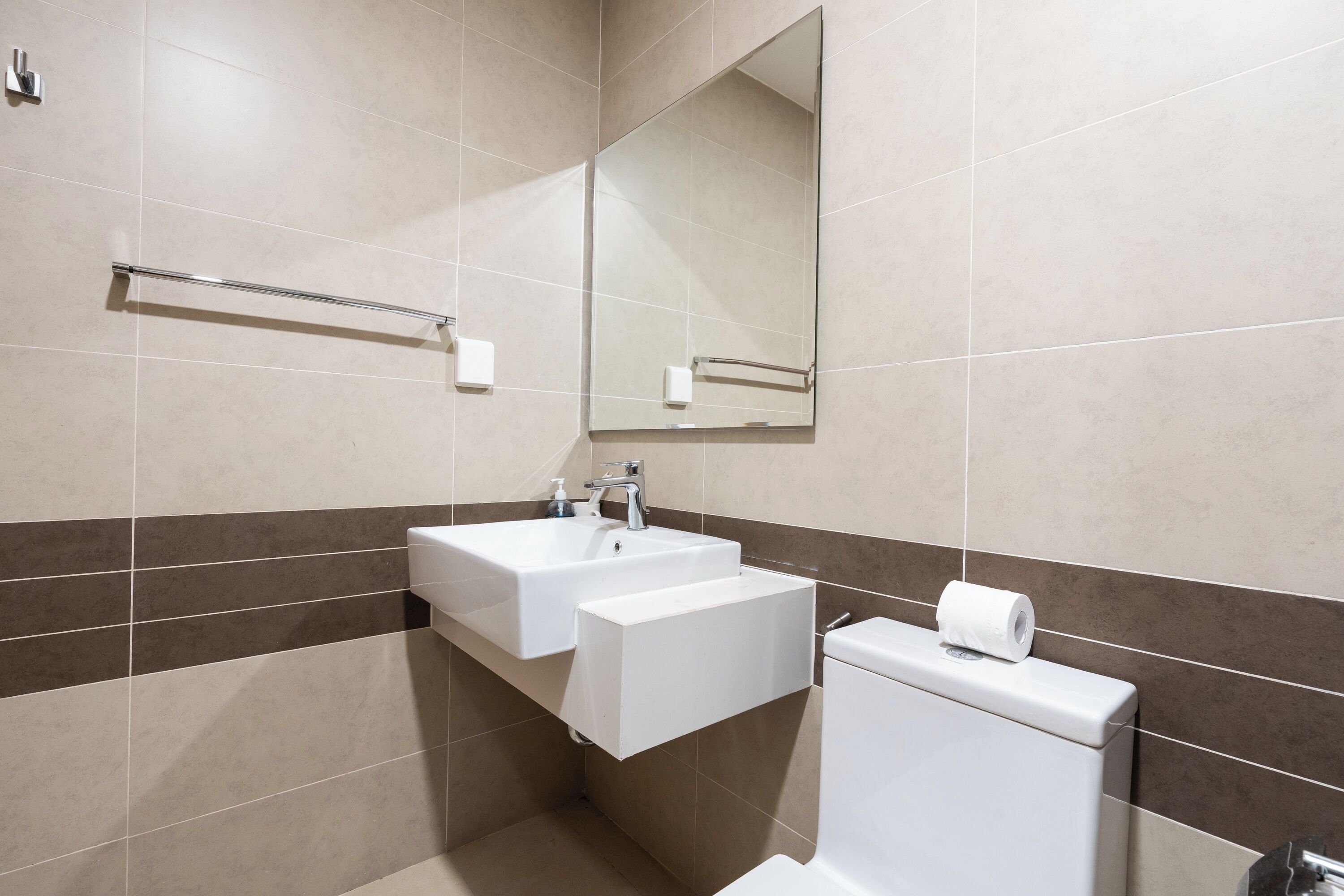 A modern bathroom with two sinks, a toilet, and a large mirror.