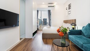 Ein modernes Hotelzimmer mit Bett, Sofa, Fernseher und Blick auf die Stadt.