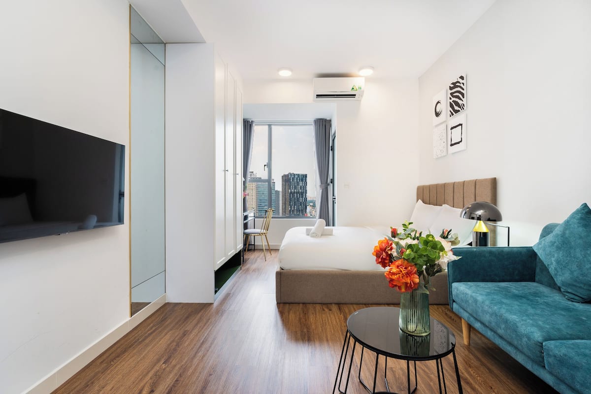 Une chambre d’hôtel moderne équipée d’un lit, d’un canapé, d’une télévision et offrant une vue sur la ville.