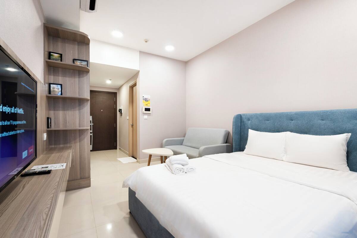 Une chambre d’hôtel comprenant un lit, une télévision, un coin salon et une porte donnant sur une autre pièce.