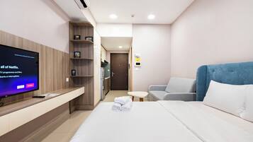 A hotel room with a bed, a TV on a wooden shelf, a sofa, and a small table.