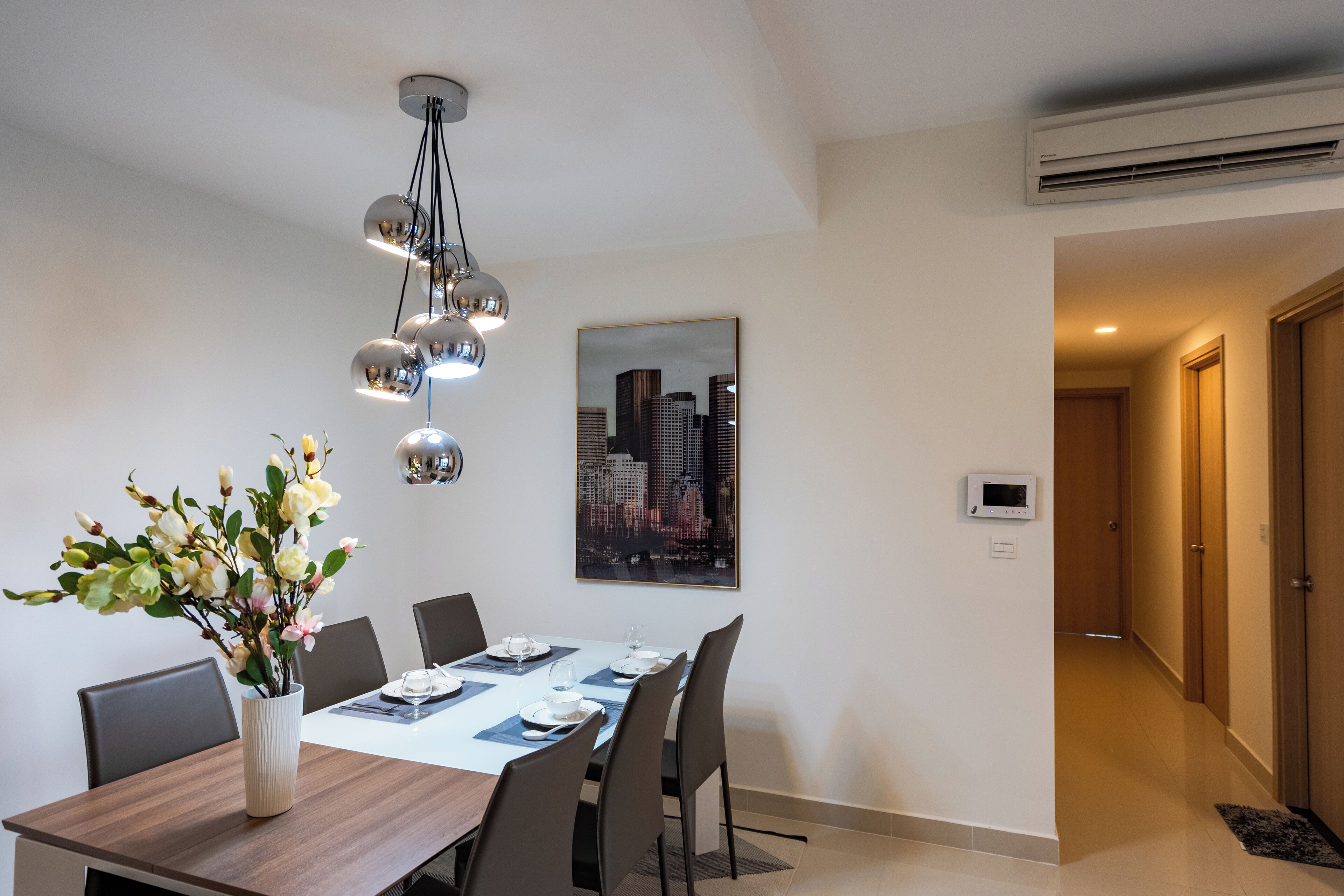 Un comedor moderno con un cuadro de la ciudad, un florero y una lámpara de techo contemporánea.