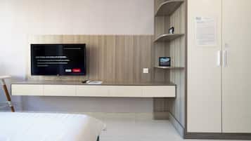 Een moderne hotelkamer met een tv, inbouwkasten, een kledingkast en een bed.
